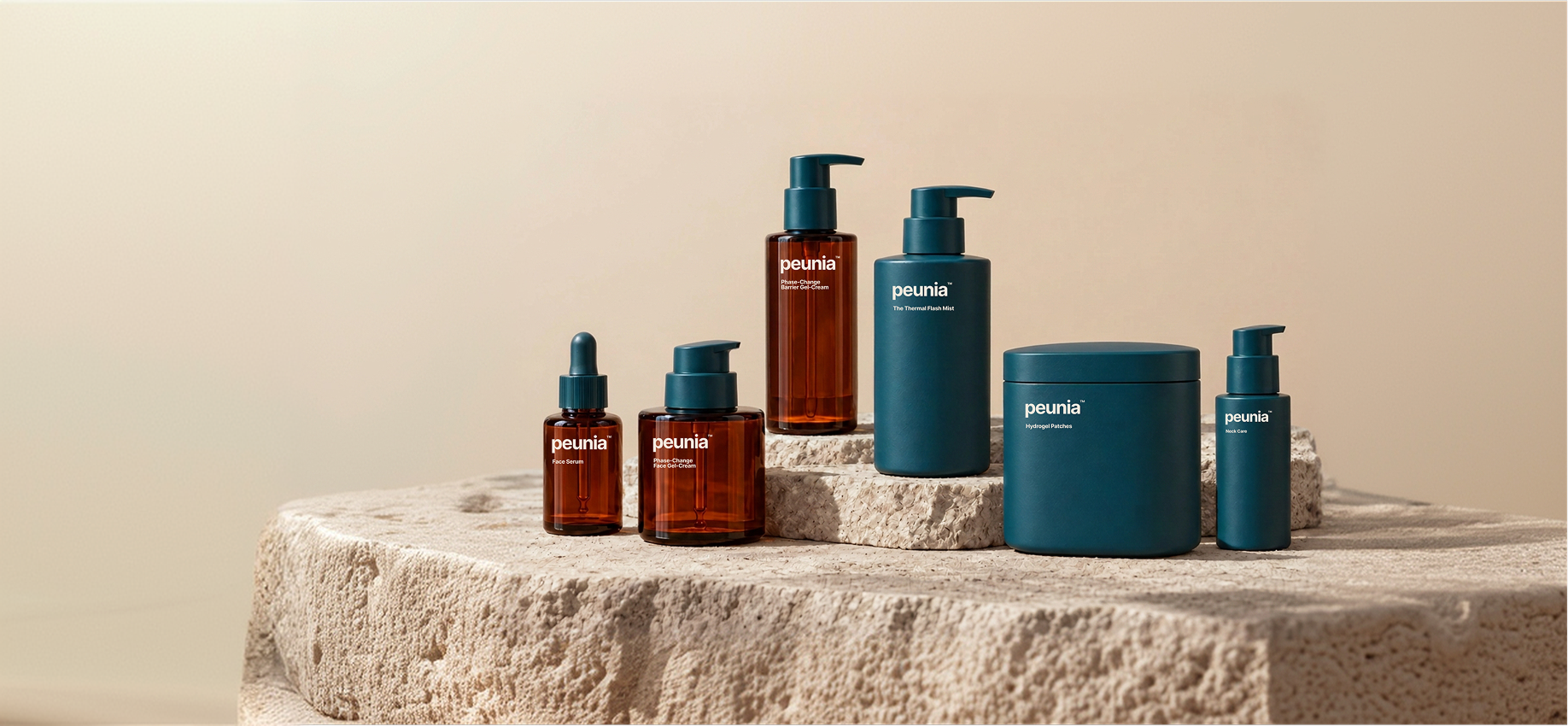 The Peunia collection in amber glass and petrol packaging, arranged on a stone plinth